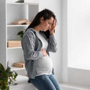 Pregnant woman experiencing a headache at home